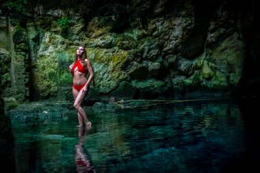 In Cuzama, Yucatan, Mexico, a stunning model revels in the vibrant hues of a cenote's blue and green waters, creating a picturesque scene of natural beauty. clipart