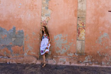 A stunning young traveler explores Telchec, Mexico's vibrant streets, basking in colorful architecture and breathtaking scenery, capturing memorable poses. clipart