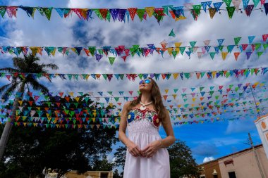 A stunning young traveler explores Telchec, Mexico's vibrant streets, basking in colorful architecture and breathtaking scenery, capturing memorable poses. clipart