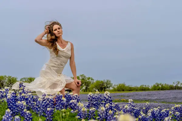 stock image A beautiful brunette model enjoys a field of Bluebonnet flowers on a spring day