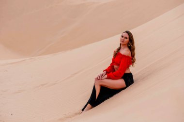 Zarif model kum tepelerindeki doğanın güzelliğini kucaklıyor, engin, doğal ihtişamın arkaplanına karşı zarafeti simgeliyor.