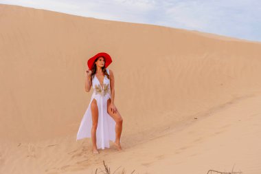 Zarif model kum tepelerindeki doğanın güzelliğini kucaklıyor, engin, doğal ihtişamın arkaplanına karşı zarafeti simgeliyor.