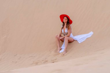 Zarif model kum tepelerindeki doğanın güzelliğini kucaklıyor, engin, doğal ihtişamın arkaplanına karşı zarafeti simgeliyor.