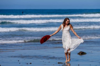 Nefes kesen kadın kumsaldaki mutluluğun tadını çıkarıyor, bir rıhtımın yanında, açık mavi gökyüzünün altında, deniz kıyısında mükemmel bir günün dinginliğini kucaklıyor.