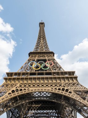 Paris 'teki Eyfel Kulesi, Olimpiyat yüzükleriyle süslenmiş, 2024 Yaz Olimpiyatları için göz alıcı bir süs olarak parlıyor, ikonik gökyüzüne karşı oyunların ruhunu ve birliği simgeliyor..