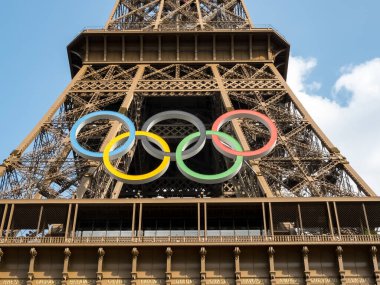 Paris 'teki Eyfel Kulesi, Olimpiyat yüzükleriyle süslenmiş, 2024 Yaz Olimpiyatları için göz alıcı bir süs olarak parlıyor, ikonik gökyüzüne karşı oyunların ruhunu ve birliği simgeliyor..