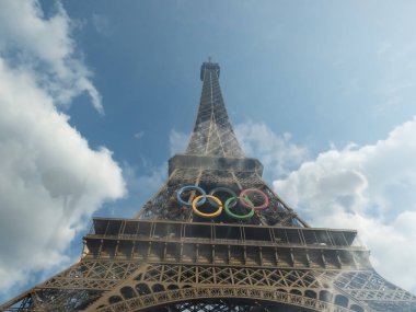 Paris 'teki Eyfel Kulesi, Olimpiyat yüzükleriyle süslenmiş, 2024 Yaz Olimpiyatları için göz alıcı bir süs olarak parlıyor, ikonik gökyüzüne karşı oyunların ruhunu ve birliği simgeliyor..