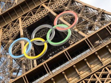 Paris 'teki Eyfel Kulesi, Olimpiyat yüzükleriyle süslenmiş, 2024 Yaz Olimpiyatları için göz alıcı bir süs olarak parlıyor, ikonik gökyüzüne karşı oyunların ruhunu ve birliği simgeliyor..