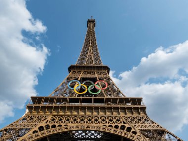 Paris 'teki Eyfel Kulesi, Olimpiyat yüzükleriyle süslenmiş, 2024 Yaz Olimpiyatları için göz alıcı bir süs olarak parlıyor, ikonik gökyüzüne karşı oyunların ruhunu ve birliği simgeliyor..