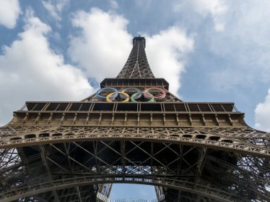 Paris 'teki Eyfel Kulesi, Olimpiyat yüzükleriyle süslenmiş, 2024 Yaz Olimpiyatları için göz alıcı bir süs olarak parlıyor, ikonik gökyüzüne karşı oyunların ruhunu ve birliği simgeliyor..