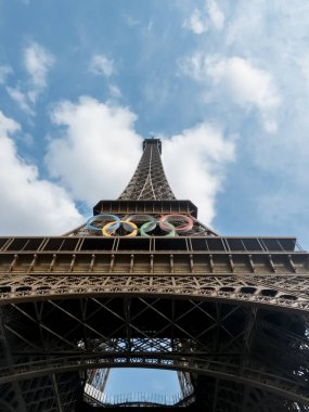 Paris 'teki Eyfel Kulesi, Olimpiyat yüzükleriyle süslenmiş, 2024 Yaz Olimpiyatları için göz alıcı bir süs olarak parlıyor, ikonik gökyüzüne karşı oyunların ruhunu ve birliği simgeliyor..