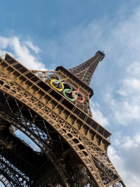 Paris 'teki Eyfel Kulesi, Olimpiyat yüzükleriyle süslenmiş, 2024 Yaz Olimpiyatları için göz alıcı bir süs olarak parlıyor, ikonik gökyüzüne karşı oyunların ruhunu ve birliği simgeliyor..