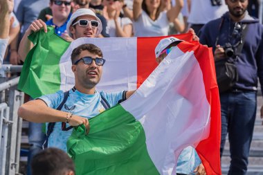 Taraftarlar, Fransa 'nın başkenti Paris' te düzenlenen 2024 Paris Yaz Olimpiyatları sırasında Stade Tour Eiffel Stadyumu 'nda oynanan Havuz B Mens Plaj Voleybolu karşılaşmasında ulusal gurur ve heyecan göstererek en sevdikleri oyunculara destek veriyorlar..