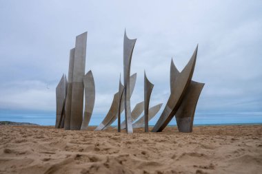 Omaha Sahili 'nde çarpıcı bir anıt olan Les Braves, D-Day kahramanlarını üç unsurla onurlandırdı: Umut, Özgürlük ve Kardeşlik. 6 Haziran 1944 'ten beri süregelen birlik, cesaret ve kardeşliği sembolize eder..