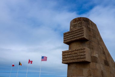 Omaha Sahili 'nin kumlarında yürüyen Normandiya Çıkarması' nın şiddetli çarpışmasının yankıları havada duruyor. Dalgalar bir zamanlar askerlerin savaştığı yere çarpar. Denizin enginliği, cesaret ve fedakârlığın kutsal anılarıyla çelişiyor..