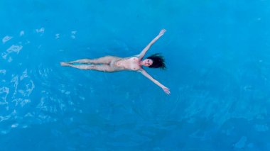 Karayip güneşinde ışıl ışıl parlıyor, özgürlüğü kucaklıyor, tenha bir havuzda çıplak yüzüyor, masmavi sularla ve parlak gökyüzüyle harmanlanmış bir güzellik görüntüsü.