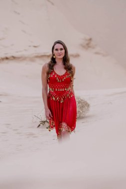 Zarif model kum tepelerindeki doğanın güzelliğini kucaklıyor, engin, doğal ihtişamın arkaplanına karşı zarafeti simgeliyor.