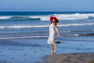 Nefes kesen kadın kumsaldaki mutluluğun tadını çıkarıyor, bir rıhtımın yanında, açık mavi gökyüzünün altında, deniz kıyısında mükemmel bir günün dinginliğini kucaklıyor.