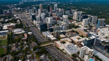 Aerial views of Atlanta showcase a vibrant cityscape with sleek skyscrapers, lush green spaces, and iconic landmarks like Mercedes-Benz Stadium. Highways, railroads, and hills weave through this bustling metropolis. clipart