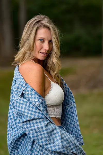 stock image A beautiful blonde model enjoys the late summer sun outdoors. Surrounded by lush greenery and soft sunlight, she radiates warmth and elegance in the serene, golden light.