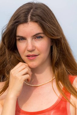 Göz kamaştırıcı bir kızıl saçlı model, marinanın pırıl pırıl mavisiyle çevrili ılık bahar güneşinde güneşleniyor. Yelkenliler yavaşça sallanıyor. Açık deniz, sonsuz uzaklığa uzanıyor..