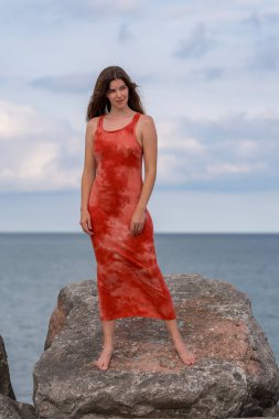 Göz kamaştırıcı bir kızıl saçlı model, marinanın pırıl pırıl mavisiyle çevrili ılık bahar güneşinde güneşleniyor. Yelkenliler yavaşça sallanıyor. Açık deniz, sonsuz uzaklığa uzanıyor..