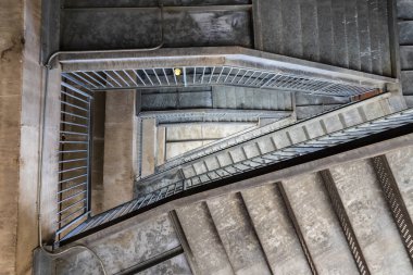 Beton bir merdivenin havadan görünüşü soyut tasarımını gösteriyor, birden fazla katı gösteriyor. Simetrik şekil ve ince tırabzanlar çarpıcı bir görüntü yaratıyor, hepsi yalnızlık içinde, etrafta kimse olmadan..