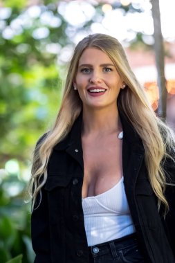 Işıl ışıl sarışın bir kadın kıtır sonbahar havasının tadını çıkarıyor. Gözleri altın güneş ışığında parıldıyor. Sıcak parıltı, onun genç tenini ön plana çıkarıyor. Açık havada güzellik ve huzur dolu mükemmel bir an yaratıyor..