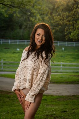 Çekici esmer, narin iç çamaşırlı güneyli kadın ılık bahar esintisinin tadını çıkarıyor, dalgalı saçları yavaşça akıyor. Kameraya özgüvenli bir poz veriyor, zarafet ve doğal güzellik yayıyor..