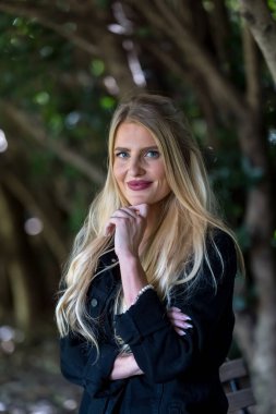 Işıl ışıl sarışın bir kadın kıtır sonbahar havasının tadını çıkarıyor. Gözleri altın güneş ışığında parıldıyor. Sıcak parıltı, onun genç tenini ön plana çıkarıyor. Açık havada güzellik ve huzur dolu mükemmel bir an yaratıyor..