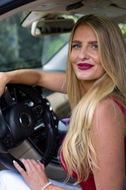 Muhteşem sarışın bir kadın beyaz jipinin içinde sevgilisiyle şakalaşıyor. Alaycı bir gülümseme ve ışıl ışıl gözleriyle, motoru çalıştırmadan önce oyalanıyor, randevuları için heyecan yaratıyor..