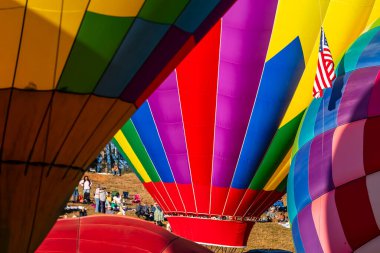 Vibrant air balloons of all shapes and colors soar into the clear blue sky, filling the air with excitement during a crisp autumn balloon fest. The scene is breathtaking against the season's beauty. clipart