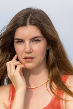 Göz kamaştırıcı bir kızıl saçlı model, marinanın pırıl pırıl mavisiyle çevrili ılık bahar güneşinde güneşleniyor. Yelkenliler yavaşça sallanıyor. Açık deniz, sonsuz uzaklığa uzanıyor..