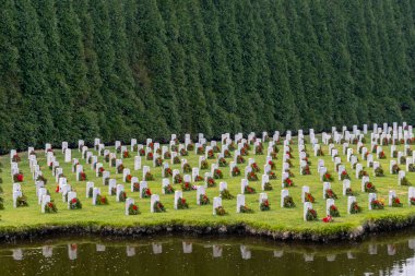 Bir tepenin üstünde, beyaz mezar taşları ve Amerikan bayrağıyla gazi mezarlığı derin bir onur, fedakârlık ve sürekli ulusal gururu çağrıştırıyor..