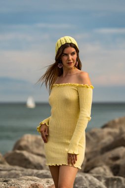 Göz kamaştırıcı bir kızıl saçlı model, marinanın pırıl pırıl mavisiyle çevrili ılık bahar güneşinde güneşleniyor. Yelkenliler yavaşça sallanıyor. Açık deniz, sonsuz uzaklığa uzanıyor..