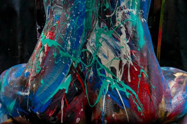 Bir model zarif bir şekilde poz verir, vücudu canlı vücut boyasıyla süslenir, onu canlı bir tuvale dönüştüren parlak, süpürge darbeleriyle. Her renk ve çizgi onu canlandırıyor..