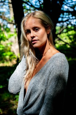 Büyüleyici bir sarışın, narin iç çamaşırlarıyla yemyeşil tarlalar ve çiçek açan çiçeklerin arasında poz vererek baharın sıcağında güneşleniyor. Doğanın güzelliğini kusursuz bir şekilde kucaklayan neşe ve zarafet saçıyor..