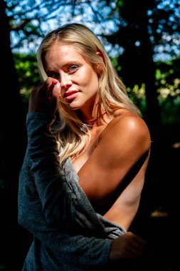 Büyüleyici bir sarışın, narin iç çamaşırlarıyla yemyeşil tarlalar ve çiçek açan çiçeklerin arasında poz vererek baharın sıcağında güneşleniyor. Doğanın güzelliğini kusursuz bir şekilde kucaklayan neşe ve zarafet saçıyor..