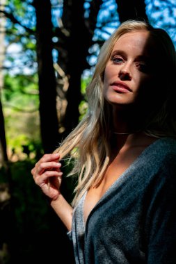 Büyüleyici bir sarışın, narin iç çamaşırlarıyla yemyeşil tarlalar ve çiçek açan çiçeklerin arasında poz vererek baharın sıcağında güneşleniyor. Doğanın güzelliğini kusursuz bir şekilde kucaklayan neşe ve zarafet saçıyor..