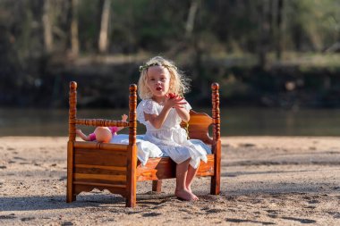 A beautiful young girl plays joyfully by a sparkling creek, her laughter harmonizing with the gentle flow of water. She twirls in the warm spring sunshine, embracing the beauty of nature all around. clipart