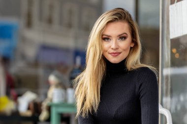 Muhteşem sarışın bir kadın, rahat bir elbise ve cekete sarılmış küçük bir kasabada geziniyor. Altın yapraklarla çevrili, sıcacık gülümsüyor, temiz havanın ve büyüleyici manzaranın tadını çıkarıyor..