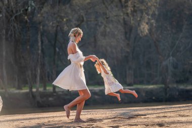 Bir anne ve güzel kızı, huzurlu bir dere kenarında gülüp eğleniyorlar. Doğanın nazik sesleriyle çevrili bu güzel bahar gününde özel bağlarını korurlar..
