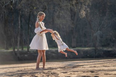 Bir anne ve güzel kızı, huzurlu bir dere kenarında gülüp eğleniyorlar. Doğanın nazik sesleriyle çevrili bu güzel bahar gününde özel bağlarını korurlar..