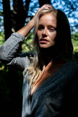 Büyüleyici bir sarışın, narin iç çamaşırlarıyla yemyeşil tarlalar ve çiçek açan çiçeklerin arasında poz vererek baharın sıcağında güneşleniyor. Doğanın güzelliğini kusursuz bir şekilde kucaklayan neşe ve zarafet saçıyor..