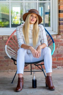 Şık giyinmiş, göz kamaştırıcı genç bir sarışın açık hava alışveriş merkezinde gazoz içiyor. Güneş onu sıcağa boğuyor. O, canlı ve açık havada esen enerjiyi ve rahatlatıcı esintiyi içine çekerken..