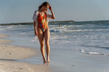 Çekici bir kadın plajda kıvrımlarını gösteren bir bikiniyle rahatlar. Soğuk suyun ve güneşin altında güneşlenmenin tadını çıkarıyor. Güneş ışınlarıyla sırılsıklam olurken altın bronzlaşmayı da..