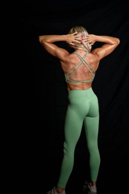 Göz kamaştırıcı atletik formda bir model stüdyoda güven içinde poz veriyor, yumuşak ışıklandırmayla vurgulanmış kasları. Gücünü ve zarafetini sergiliyor. Göz kamaştırıcı fiziğini göstererek gösterişli, minimalist bir ortamda..