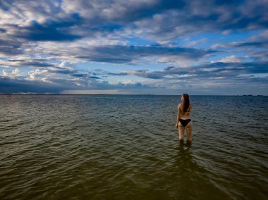 Çekici bir kadın plajda kıvrımlarını gösteren bir bikiniyle rahatlar. Soğuk suyun ve güneşin altında güneşlenmenin tadını çıkarıyor. Güneş ışınlarıyla sırılsıklam olurken altın bronzlaşmayı da..