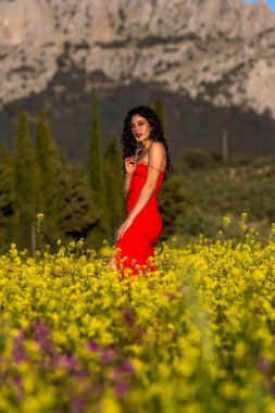 Çarpıcı bir Avrupalı model, İspanyol kır çiçeklerinin arasında yaz sonlarındaki parlaklığın tadını çıkarıyor. Doğanın güzelliğini zarafetle somutlaştırıyor..