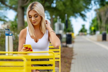 Genç bir kadın, güzel bir bahar gününde elinde telefonla tuhaf kasabasında geziniyor. Çiçekler ve ılık güneş ışığıyla çevrili halde, teknolojiyi sakin çevresinin cazibesiyle harmanlayarak bağlı kalıyor.